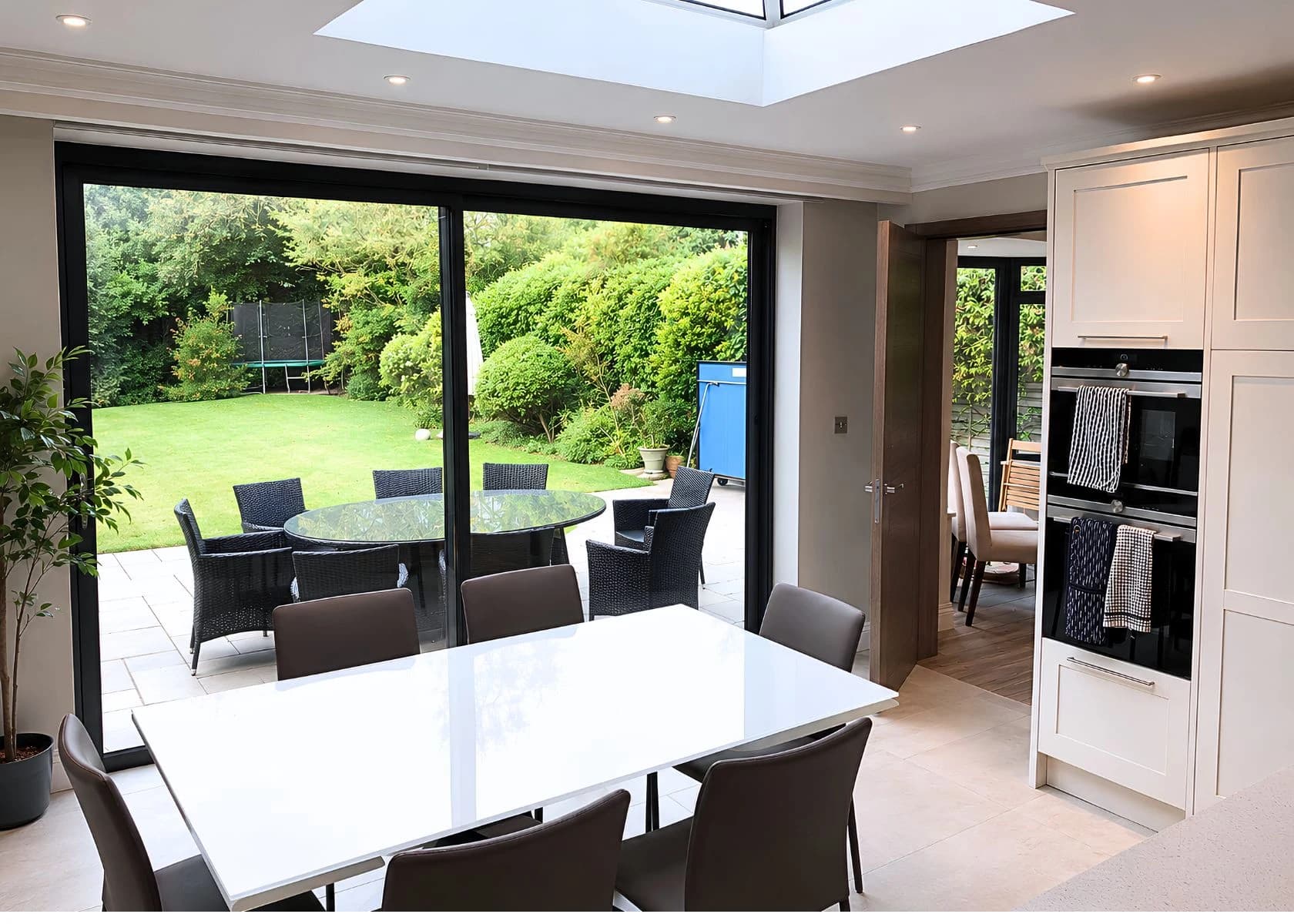Downage, Finchley: Dining space beneath a rooflight, opening onto the garden.