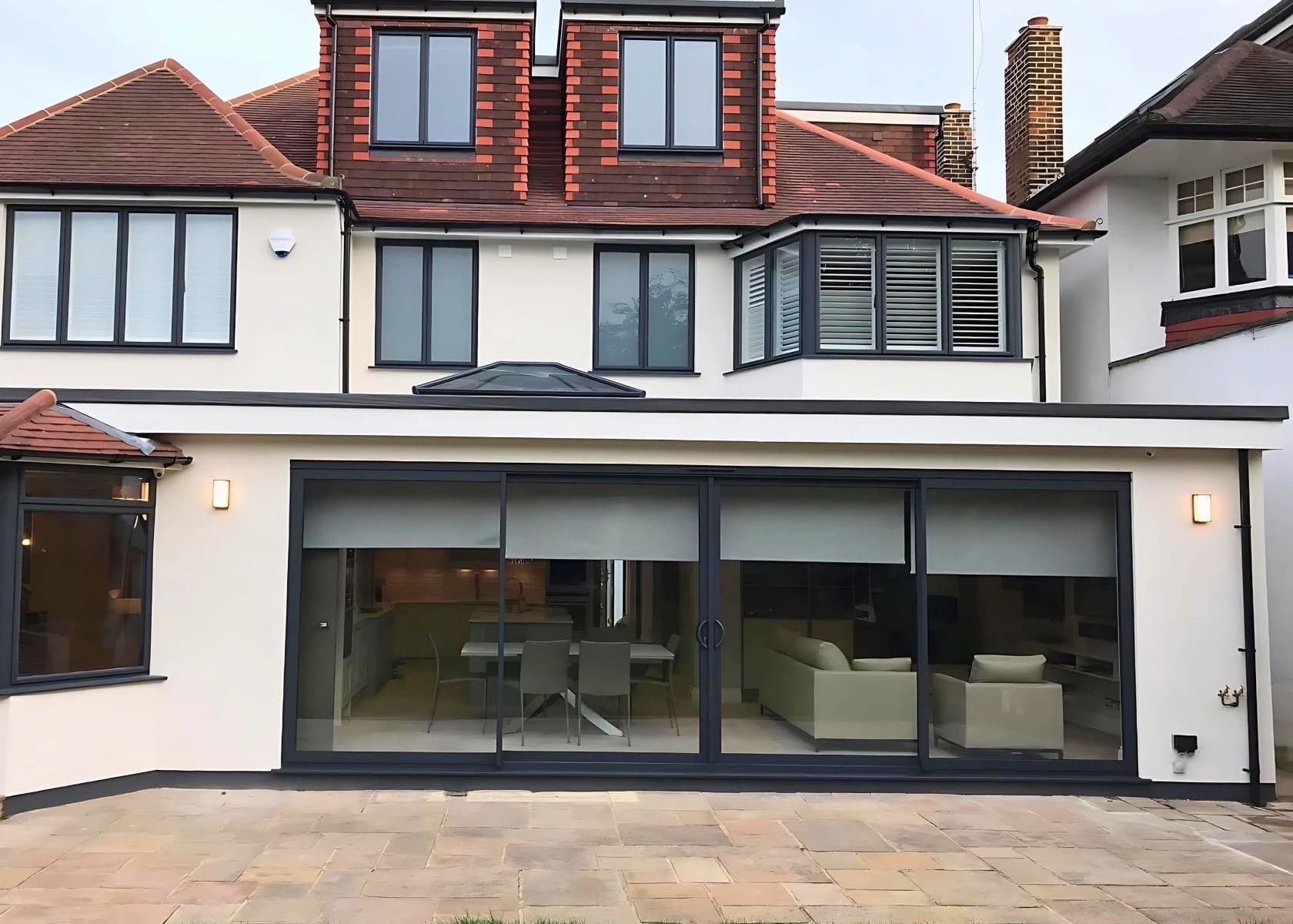 Rear elevation with wide garden doors, a paved terrace and roof-level accommodation.