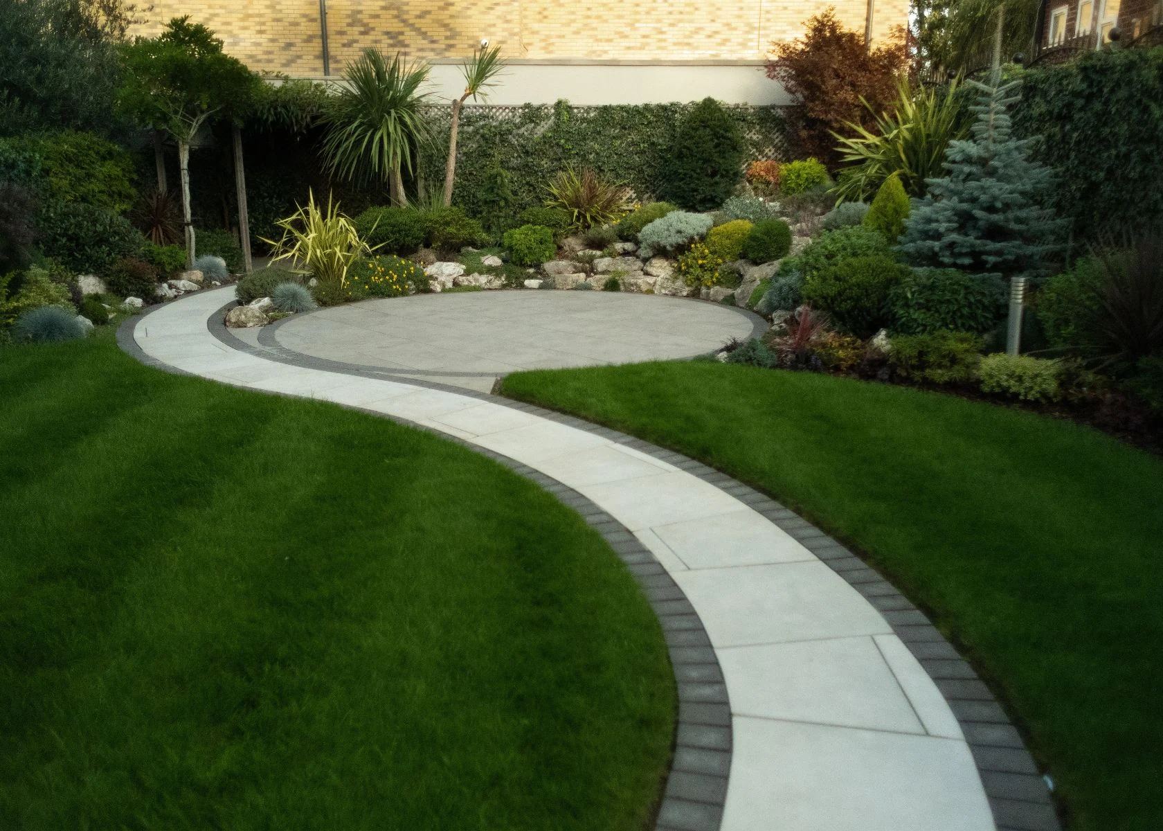 Queen Elizabeth: Garden paving, lawn and planting beside the completed house.